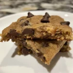 A plate of warm, gooey banana bread chocolate chip cookies, scattered with chocolate chips.