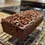 Close-up of a stack of moist double chocolate banana bread slices, with a hand taking a slice.